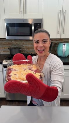 a woman is holding up a pan of food in her hands and smiling at the camera