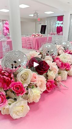 pink and white centerpieces with disco ball decorations on the tables at a party