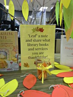 a table topped with lots of cards and paper hearts next to a sign that says leaf a note and share what library books and services you are thank