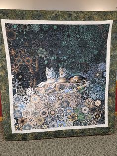 a quilt with two cats sitting on top of it