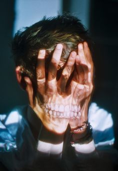 a man holding his hands to his face while wearing a skull - like mask and looking at the camera