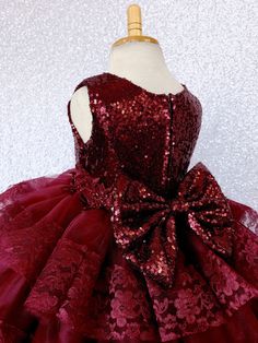 A modern country-inspired dress with cascading ruffle tiers carefully hand stitched to perfection for any upscale event or birthday! The burgundy sequin sleeveless bodice is fully lined for the ultimate comfort. Beautiful embroidery can be found across the waistline for added detail. The dress comes with a detachable sequence bow. Zipper can be found on the back of the dress. The skirt is made out of multiple rows of tulle ruffles with lace hem with four layers of tulle used on each row for a un Fitted Sleeveless Christmas Ball Gown, Sleeveless Christmas Dress With Bow, Elegant Sleeveless Princess Dress For Festive Occasions, Christmas Wedding Princess Dress With Bow, Festive Sleeveless Princess Dress For Wedding, Holiday Princess Dress With Bow For Dress-up, Sleeveless Princess Dress For Wedding And Festive Occasions, Sleeveless Princess Dress For Wedding And Party Season, Fitted Sleeveless Princess Dress For Christmas