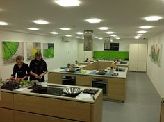 two women preparing food in a kitchen with green accenting the walls and ceiling lights