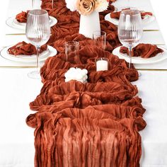 the table is set with white plates and silverware, red napkins and flowers