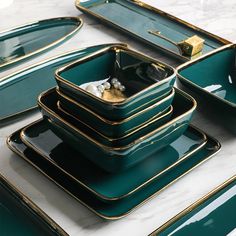 a table topped with green dishes and gold trimmings on top of each other