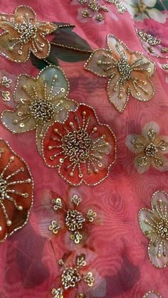 the fabric is covered with gold and red flowers on pink silk, which are embellished with sequins