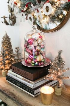 a table topped with books and christmas decorations next to a clock on top of a wall