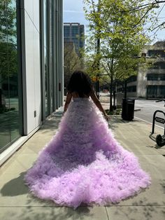 a woman is walking down the sidewalk in a dress