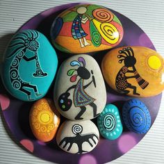 colorful painted rocks on a purple plate with polka dots