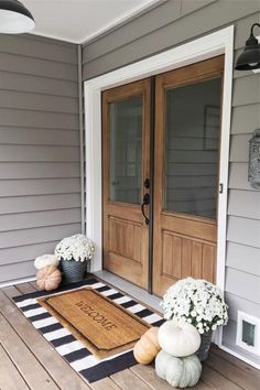 the front porch is decorated for fall with pumpkins and hydrangeas