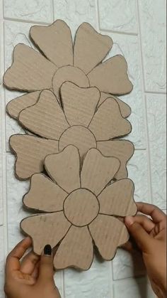 someone is making a flower out of cardboard and glues it on the floor with their hands