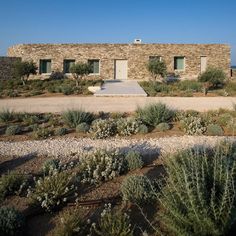 an old stone building surrounded by plants and rocks