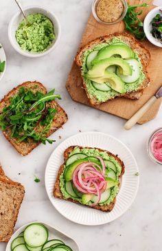 two slices of bread with cucumber and avocado on it, surrounded by other food items