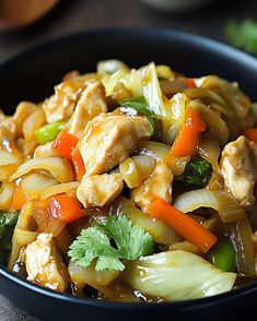 a black bowl filled with chicken, carrots and celery stir - fry