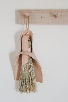 a pair of shoes hanging on a wall with a broom attached to the shoe hanger