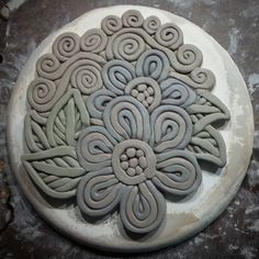 a white plate with an intricately designed design on the top, sitting on a stone surface