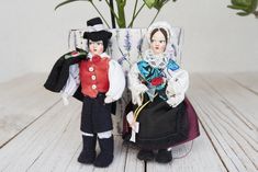 two dolls sitting next to each other in front of a vase with flowers on it