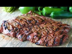 steak on a cutting board with green peppers in the background