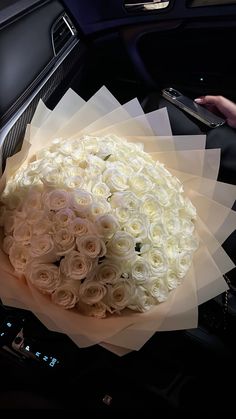 a bouquet of white roses sitting on top of a car dashboard