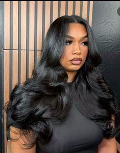 a woman with long black hair standing in front of a wall