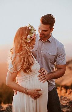 a man and woman standing next to each other on top of a hill with flowers in their hair