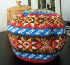 a colorful knitted hat sitting on top of a table next to a wooden box