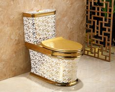 a gold toilet in a bathroom next to a wall with decorative tiles on the walls