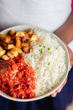 a person holding a bowl filled with rice and meat