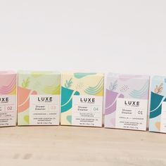 four boxes of luxury soaps are lined up on a wooden table with white background