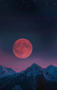 the full moon is seen over mountains at night