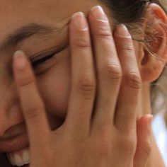 a close up of a person holding their hands to their face and covering her eyes