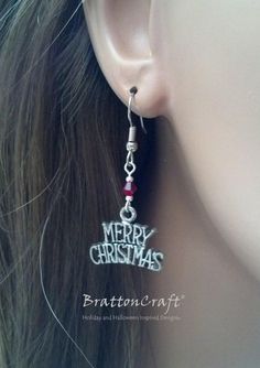 Merry Christmas! The charms on these Merry Christmas Earrings are made of lead free pewter in the USA with an antique silver finish. The red bead is Swarovski crystal and the small silver beads are silver plated. The earring is 7/8 inches wide at the bottom and the earring is 1 inch long from the end of the ear wire. The ear wire shown is stainless steel. Sterling silver ear wires with the same style are available and may be selected at checkout. Plastic earring backs are included. These festive Adjustable Earrings For Christmas Gift, Adjustable Earrings As A Christmas Gift, Adjustable Silver Christmas Earrings, Nickel-free Sterling Silver Christmas Earrings, Nickel-free Silver Earrings For Christmas, Nickel-free Sterling Silver Earrings For Christmas, Nickel Free Silver Earrings For Christmas, Holiday Silver Jewelry With Ear Wire, Christmas Silver Jewelry With Matching Earrings