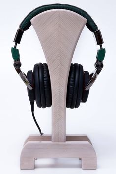 a pair of headphones sitting on top of a wooden stand in front of a white background