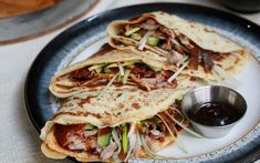 three quesadillas on a plate with dipping sauce