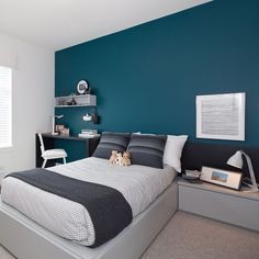 a bed room with a neatly made bed next to a night stand and desks