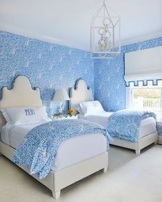 two beds in a room with blue and white wallpaper