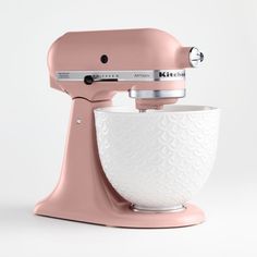 a pink mixer is sitting on a white surface