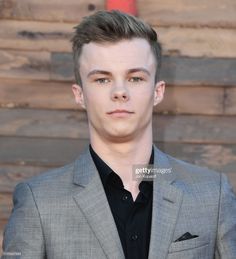 a young man in a gray suit and black shirt