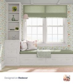 a white window seat in front of a window with flowers on the wall and green curtains