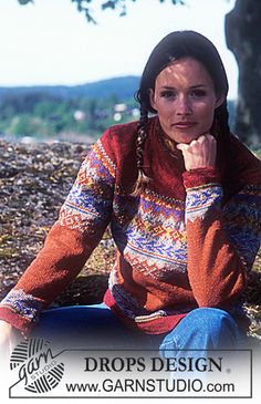 a woman sitting on the ground in front of a tree with her hand under her chin