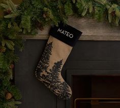 a christmas stocking hanging from a fireplace with pine cones and evergreens around it