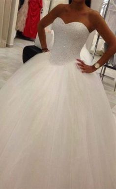 a woman standing in front of a mirror wearing a wedding dress