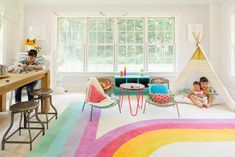 two children are sitting in their playroom with teepee tent and rainbow rugs