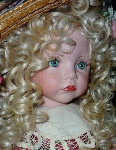 a doll with blonde hair and blue eyes wearing a straw hat