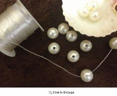 pearls and thread are on the floor next to a seashell