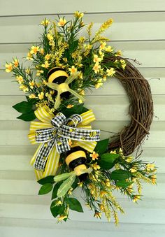 a wreath with yellow flowers and two bums hanging on the side of a house