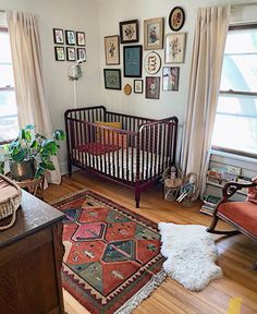 a baby crib in the corner of a room with pictures on the wall