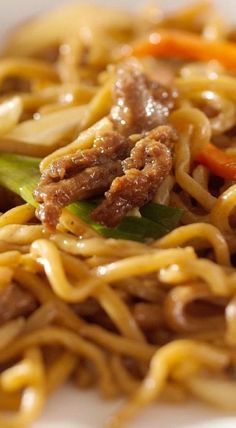 a white plate topped with noodles and meat