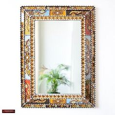 a mirror hanging on the wall above a potted plant