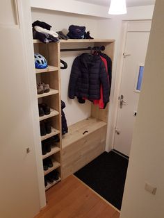 an open closet with shoes and coats hanging on the wall, next to a door